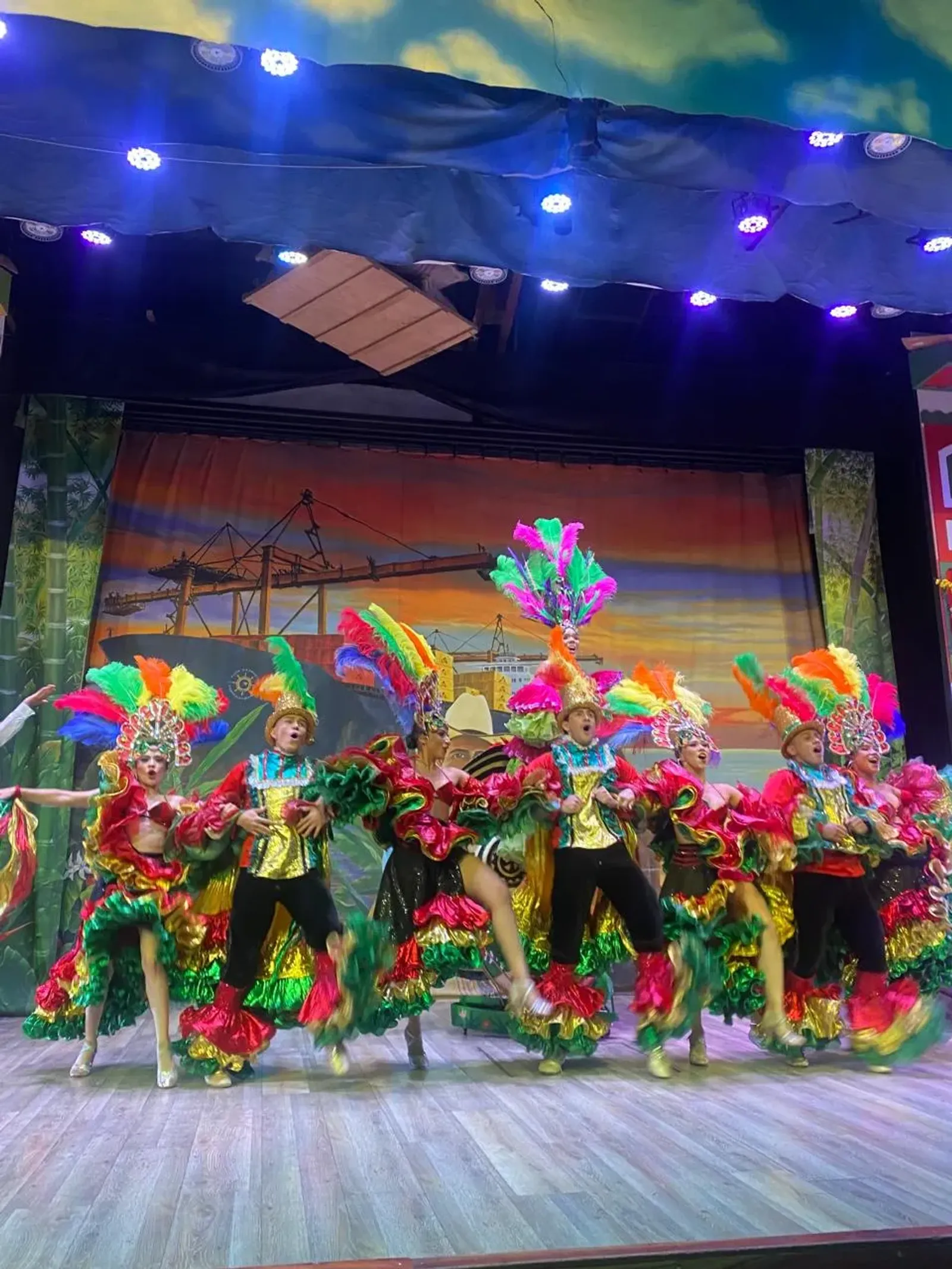 Bailarines con trajes de plumas de colores en un show cultural del Parque del Café