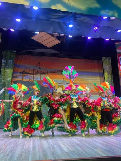 Bailarines con trajes de plumas de colores en un show cultural del Parque del Café