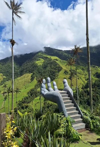 Escultura de una mano gigante con escalera, mirador en el Valle de Cocora rodeado de palmas de cera