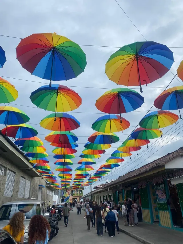 Calle de Filandia decorada con sombrillas de colores y turistas caminando