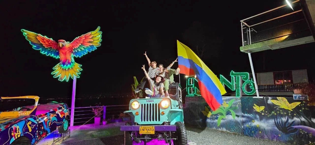 Viajeros celebrando sobre un jeep junto al letrero iluminado de Salento
