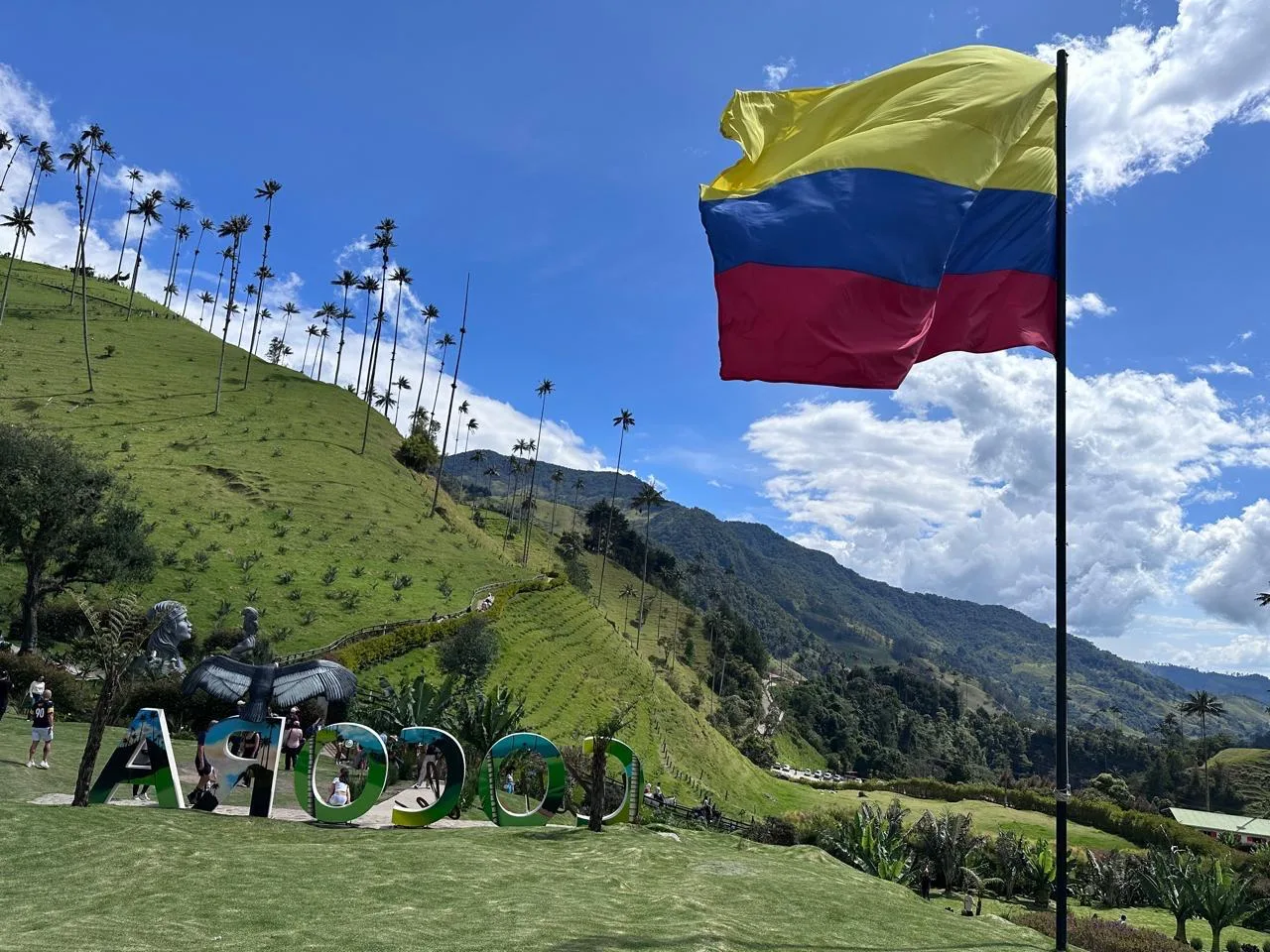 Letrero de Cocora con la bandera de Colombia y palmas de cera en la montaña